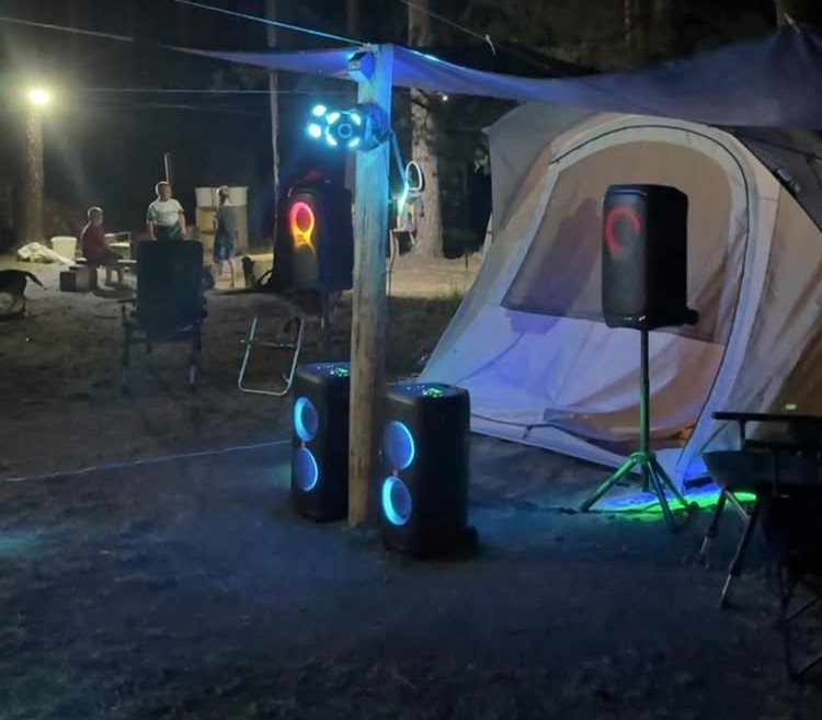 Camping tent and large glowing speakers set up for a nighttime outdoor party