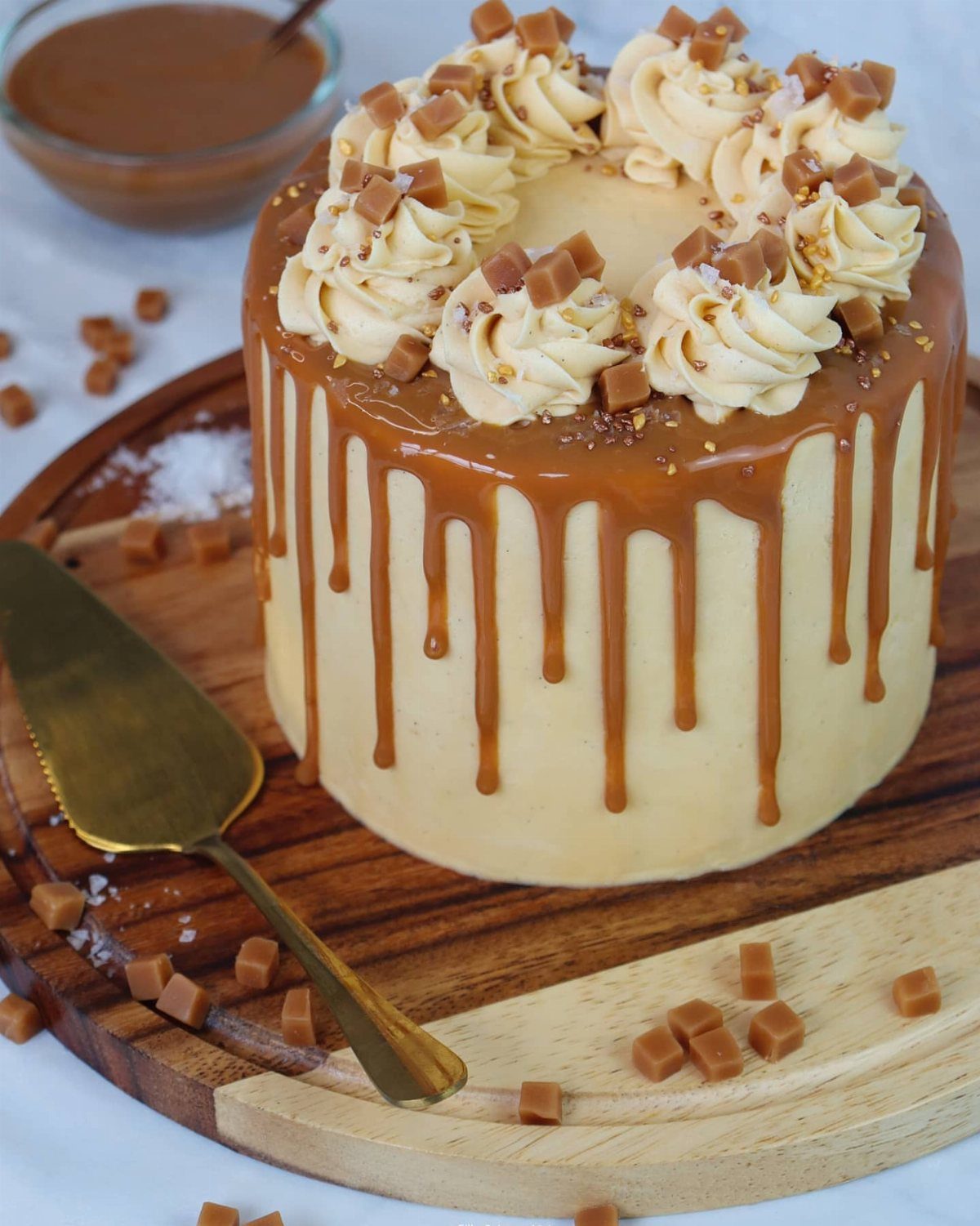 6 Inch Cake Decorating Ideas: 11 Flavors and Finishes to Try 5 Small round cake with caramel drips, buttercream swirls, and caramel cubes on wooden board