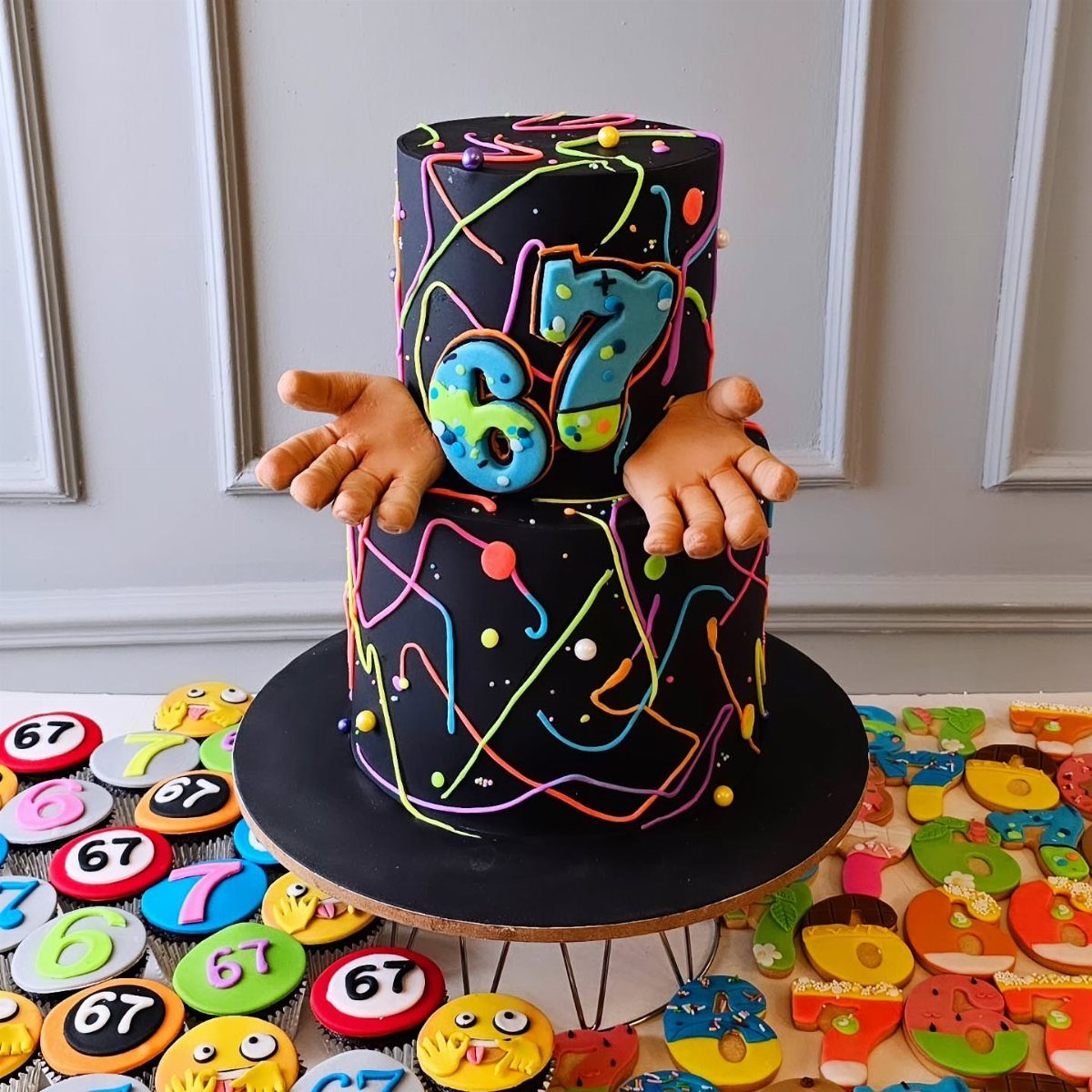 67 Cake Ideas for Birthdays: 14 Designs From Drip to Neon 14 Two-tier black cake with neon decorations and the number 67 and edible hands.