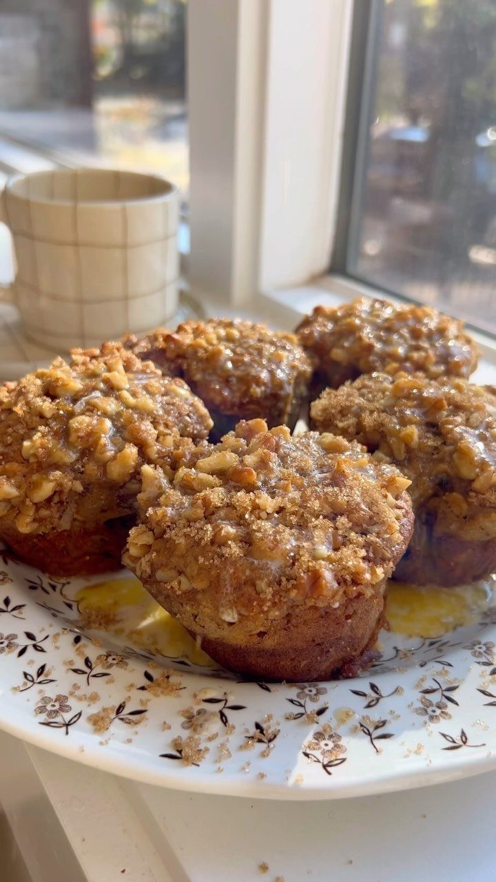 Banana muffins with glazed nut crumble topping on a white floral plate.