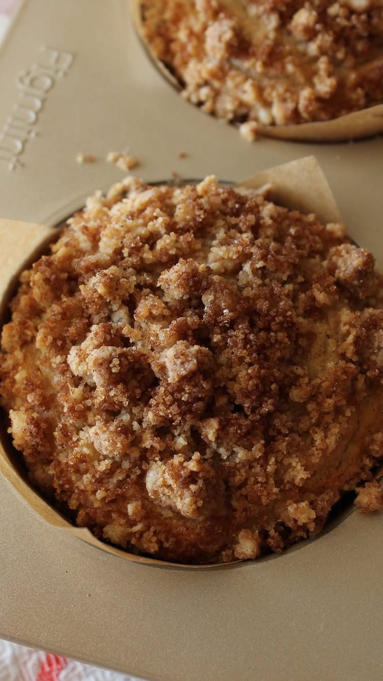 Banana muffin with a chunky, golden-brown cinnamon streusel topping in a paper liner.