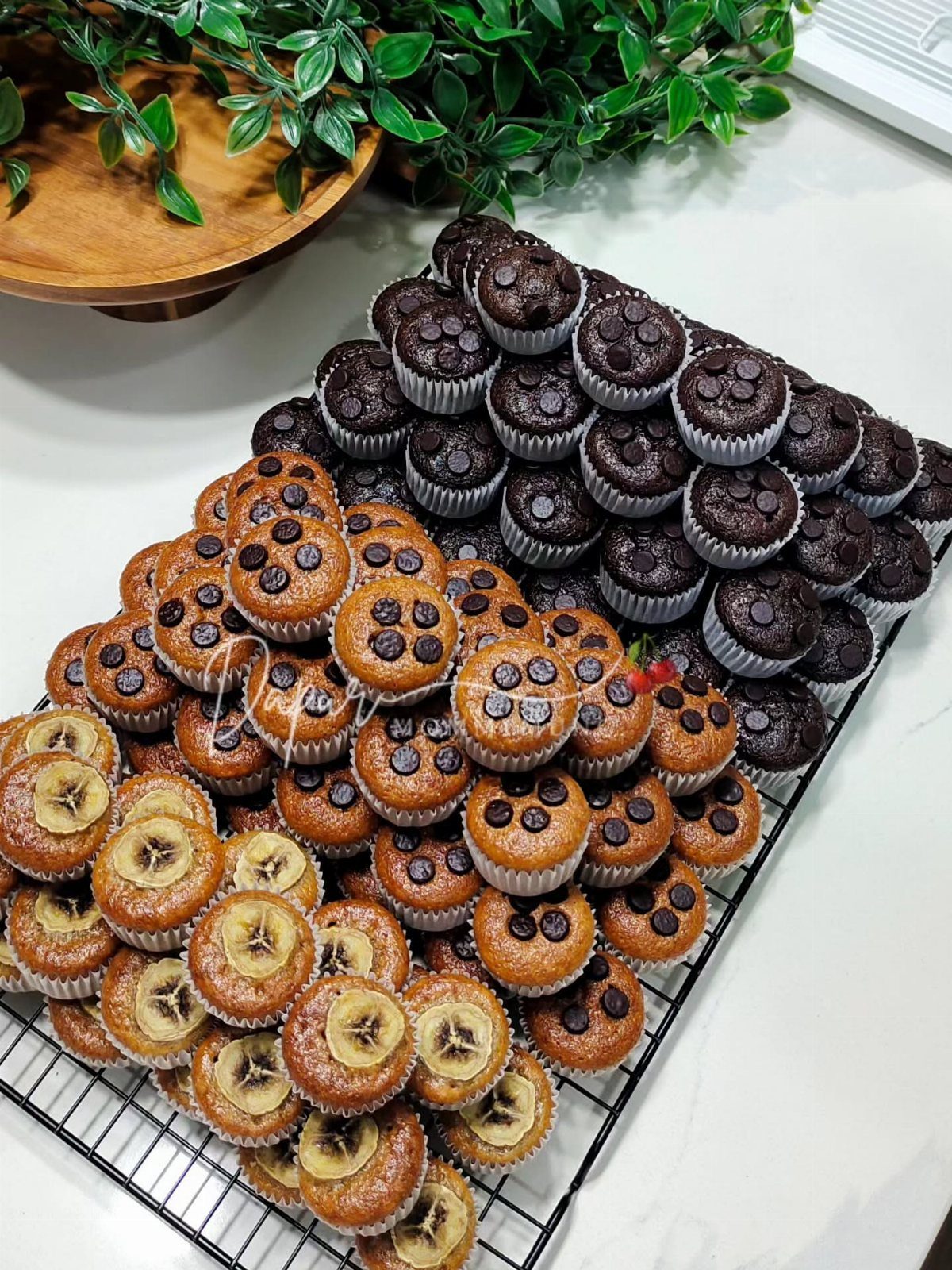 Mini banana and chocolate muffins cooling on a black wire rack.