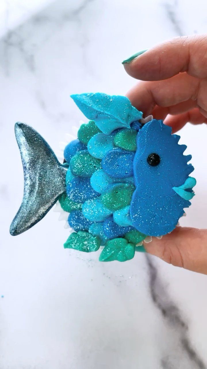 31 Beach Themed Appetizers for Parties, Picnics and Pool Days 15 Fish-shaped blue and teal candy dessert held by a hand against marble.