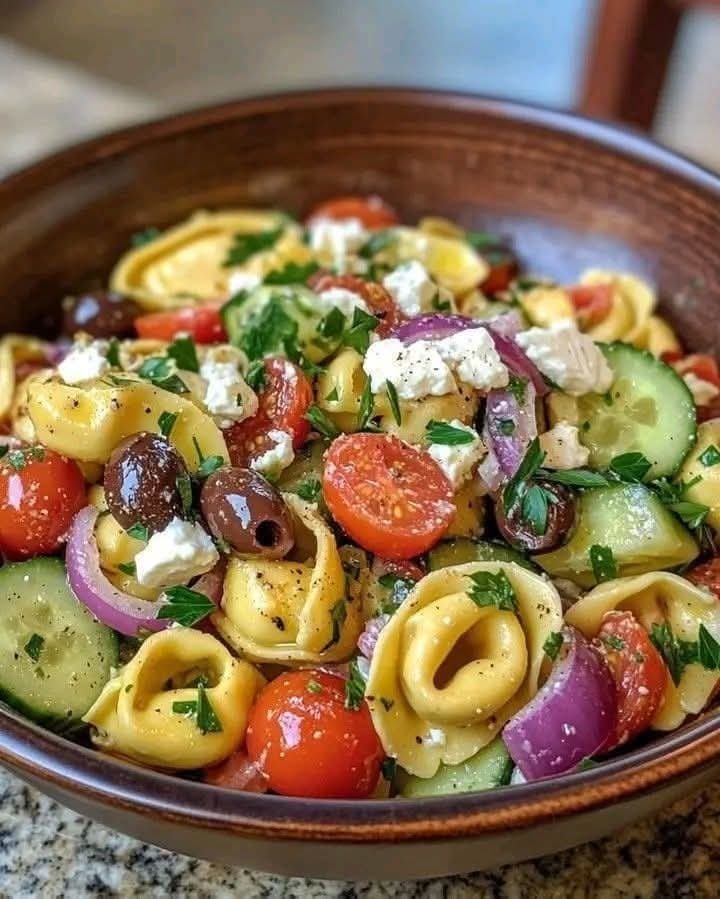 31 Beach Themed Appetizers for Parties, Picnics and Pool Days 7 Greek tortellini salad with feta, olives, and vegetables in a brown ceramic bowl.