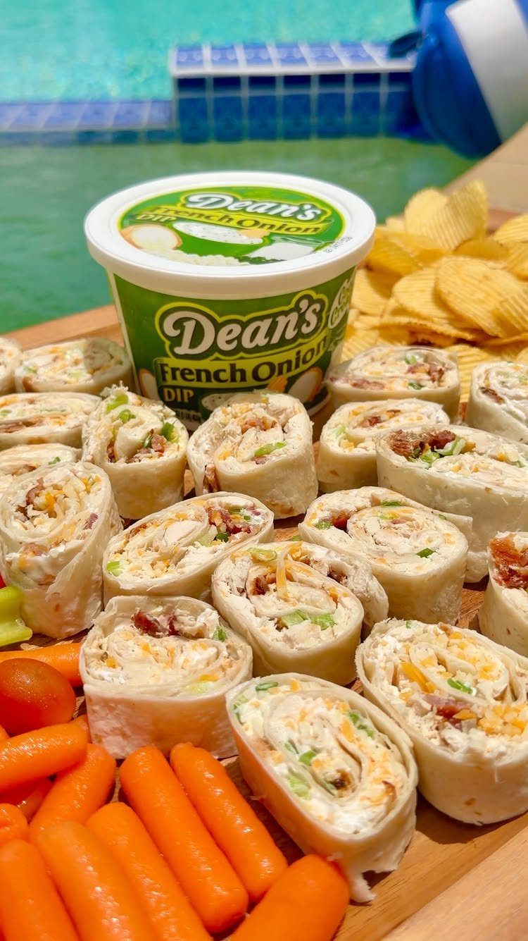 31 Beach Themed Appetizers for Parties, Picnics and Pool Days 5 Pinwheel tortilla sandwiches on a wooden platter with carrots, chips, and onion dip.