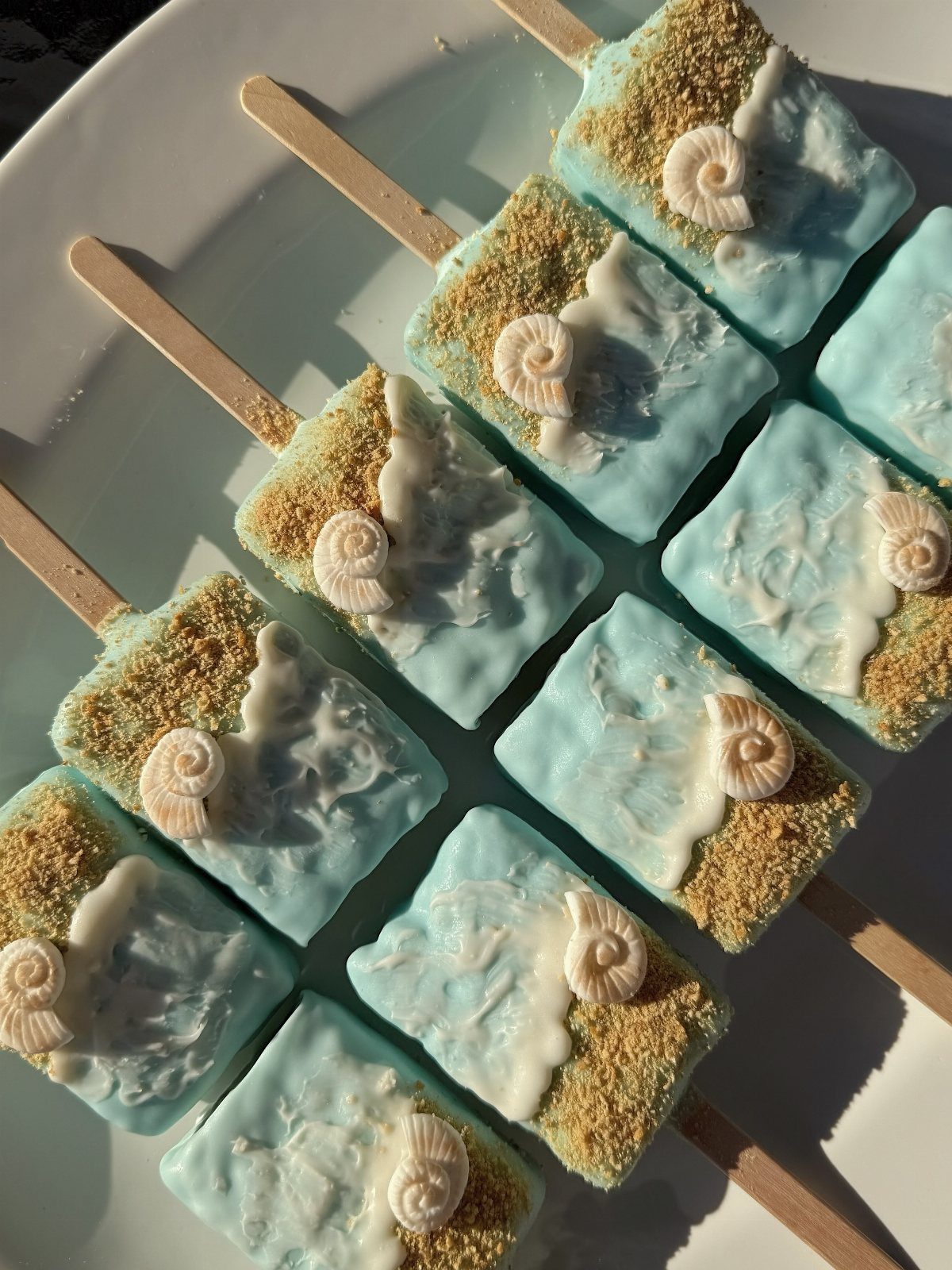 31 Beach Themed Appetizers for Parties, Picnics and Pool Days 22 Rice krispie treats decorated as beaches with blue frosting, sand, and seashell candies.