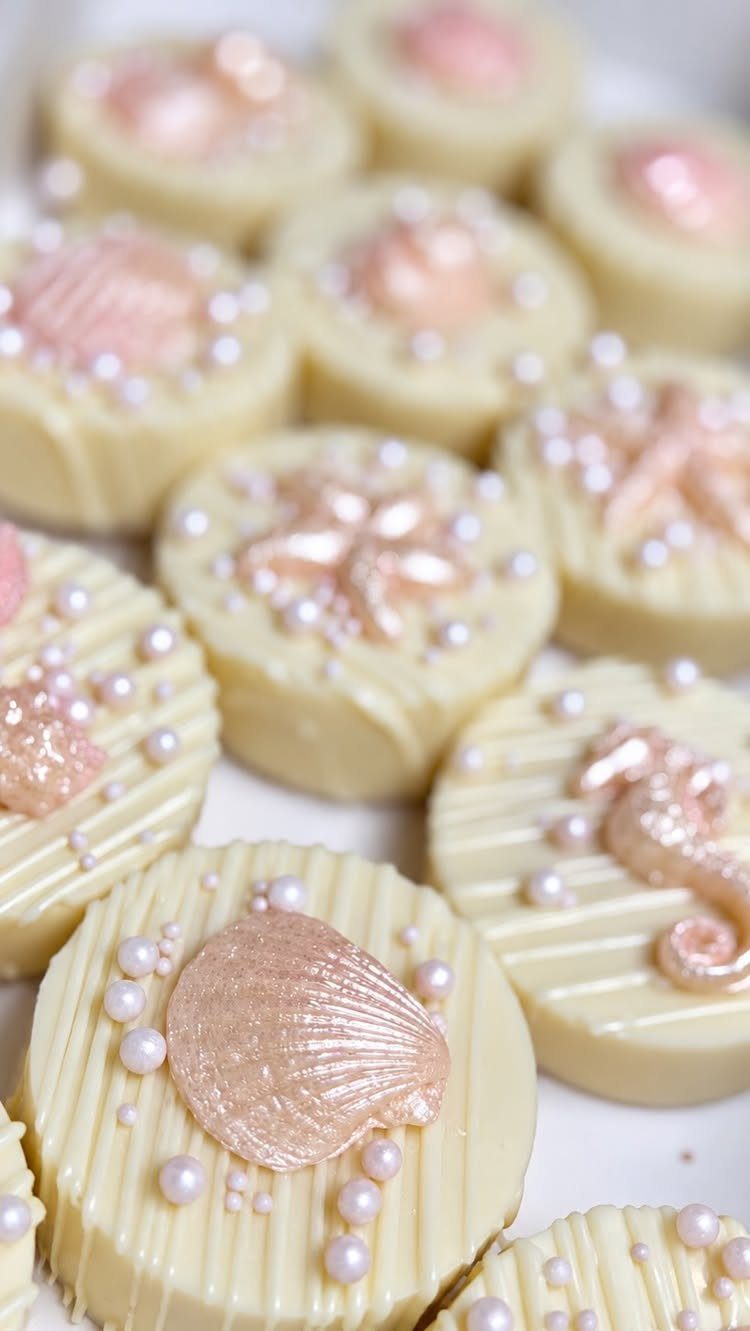 31 Beach Themed Appetizers for Parties, Picnics and Pool Days 31 White chocolate cookies decorated with pink seashells and small white edible pearls.