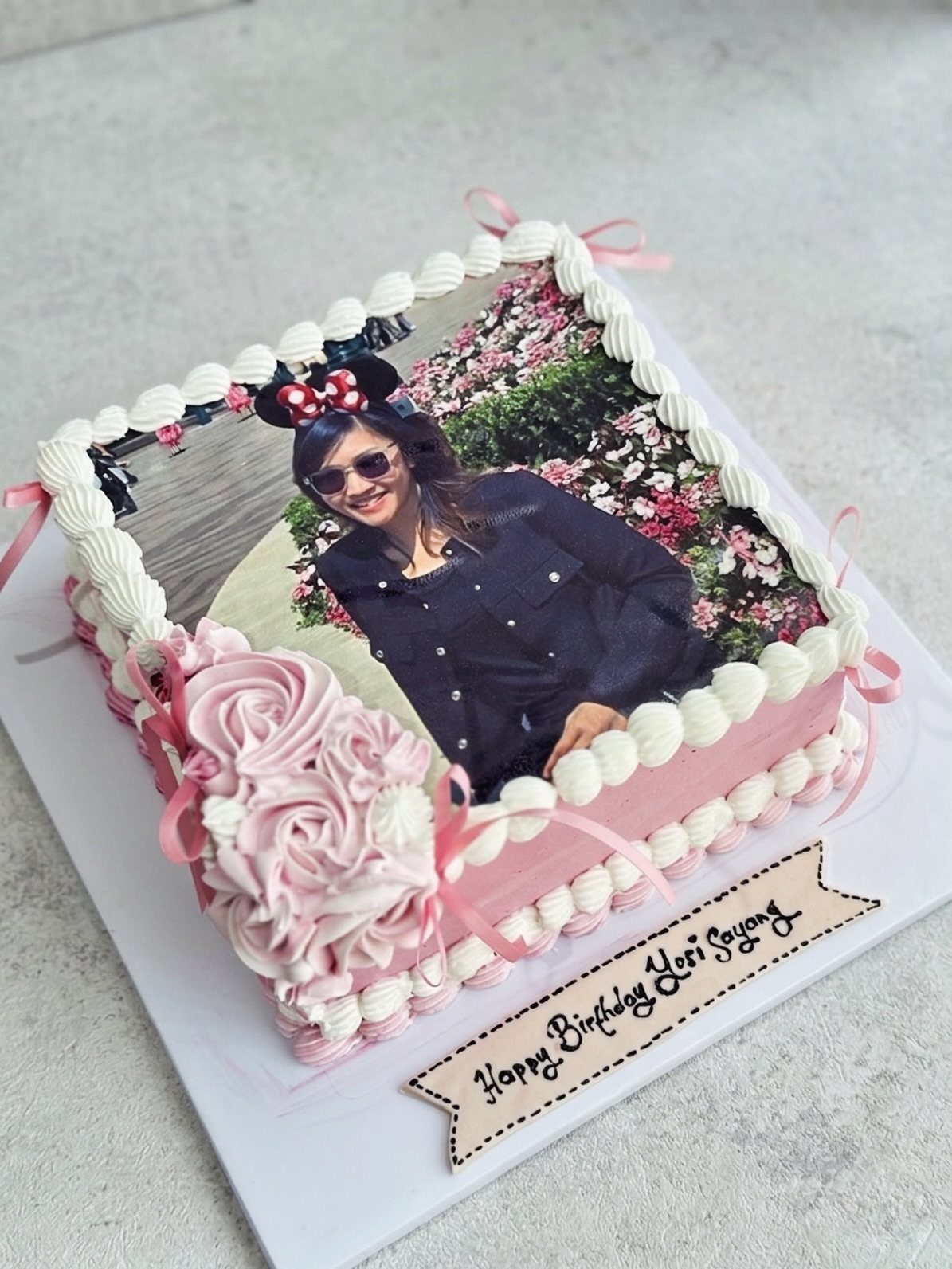 Pink birthday cake with white frosting and an edible photo of a woman.
