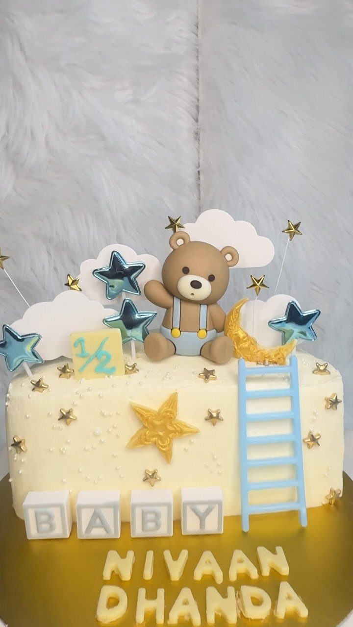 White cake with a brown fondant bear, gold crescent moon, and blue ladder.