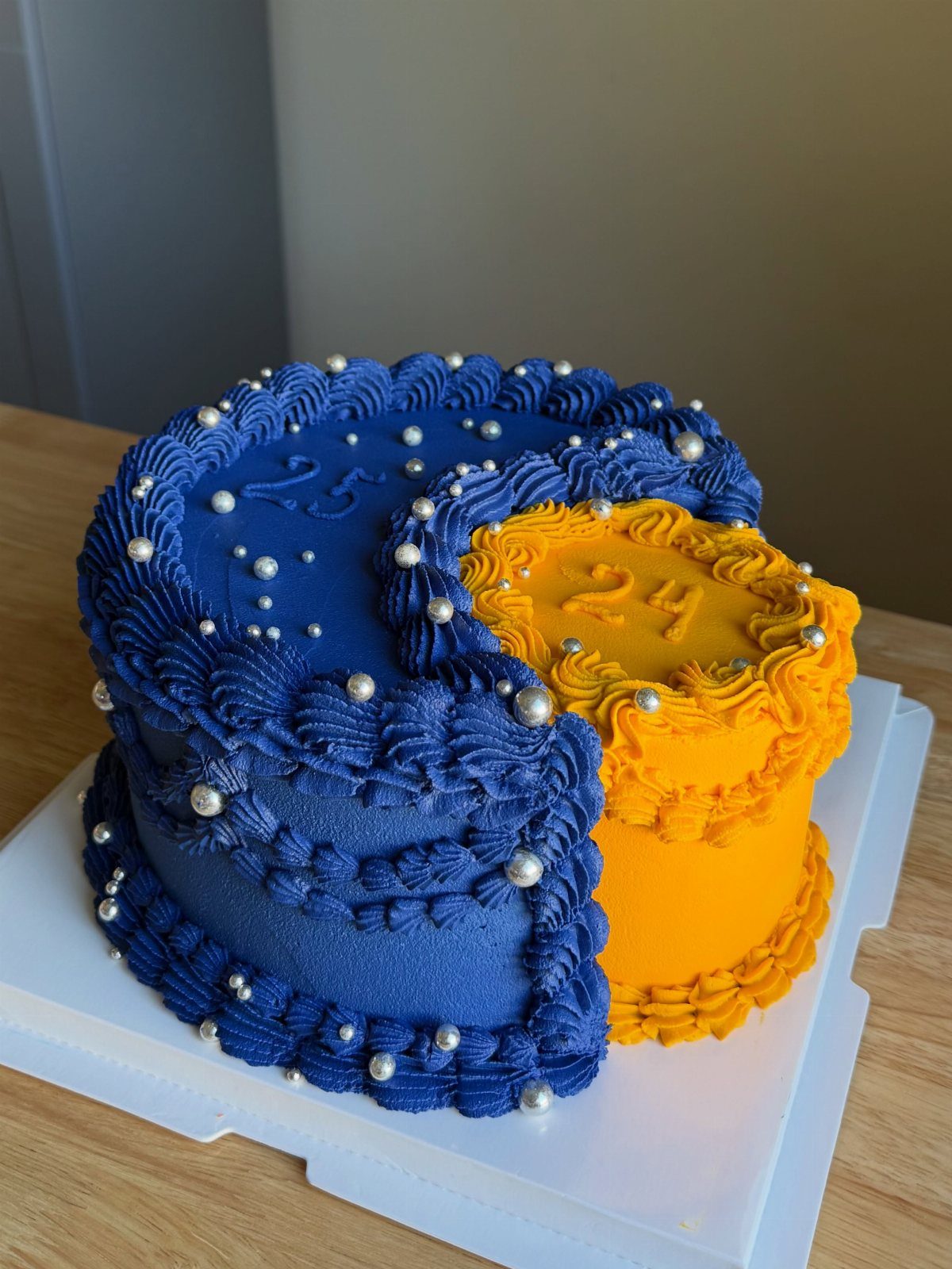 Crescent moon birthday cake with deep blue and bright yellow frosting and silver pearls.