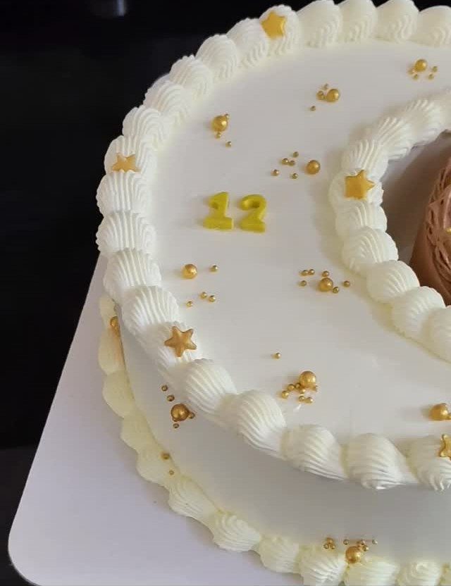 White birthday cake with a frosting crescent moon, gold stars, and number 12.