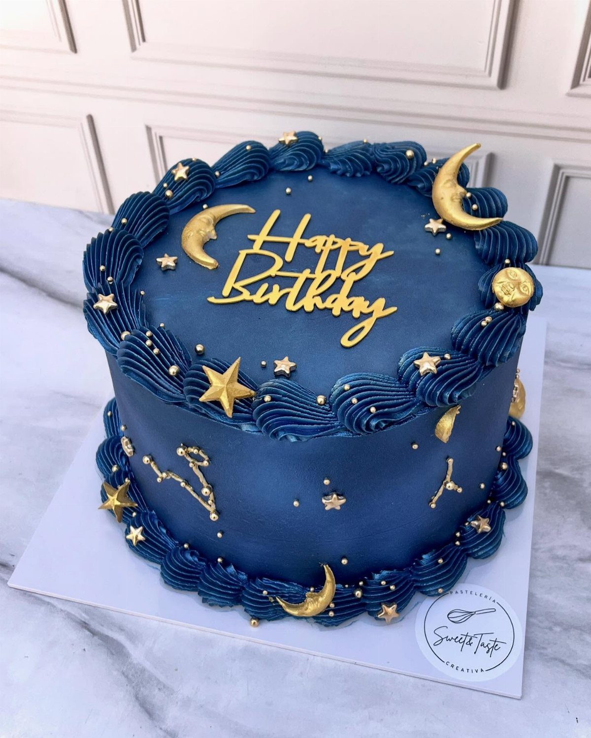 Deep blue birthday cake decorated with gold crescent moons, stars, and birthday topper.
