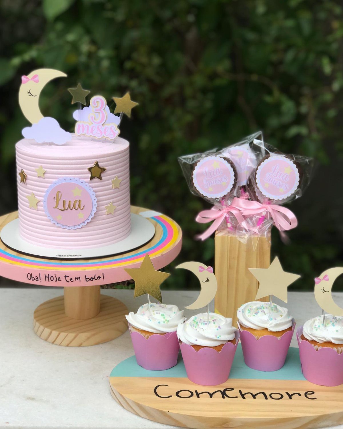 Pink birthday cake with crescent moon topper, gold stars, and matching cupcakes.