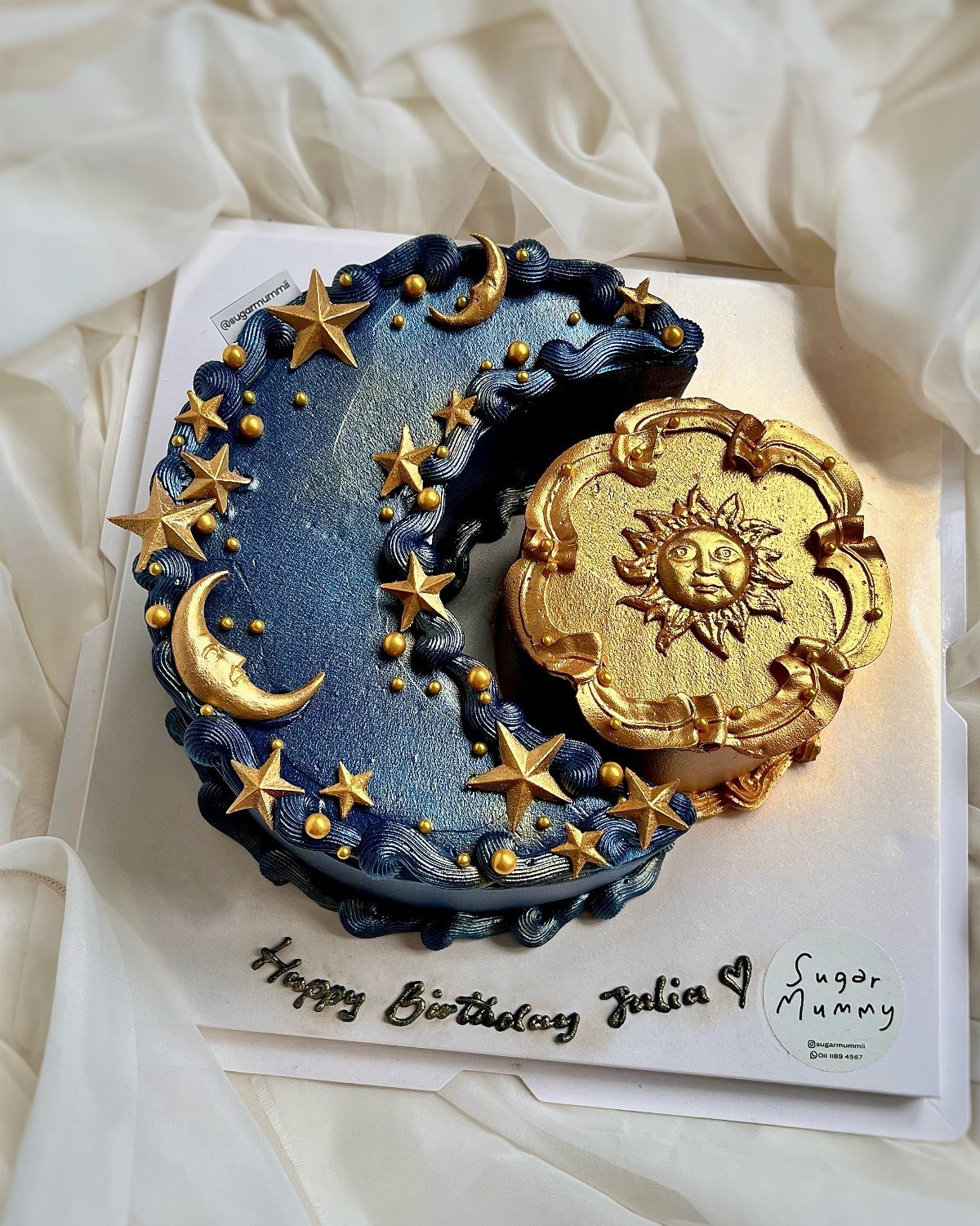 Crescent-shaped dark blue glittery cake with gold stars and a gold sun cake.