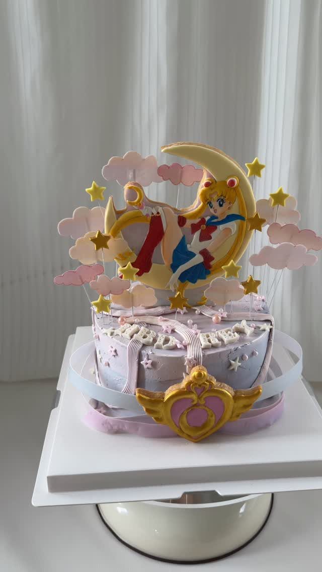 Sailor Moon cake with purple frosting, yellow crescent moon, and colorful star decorations.