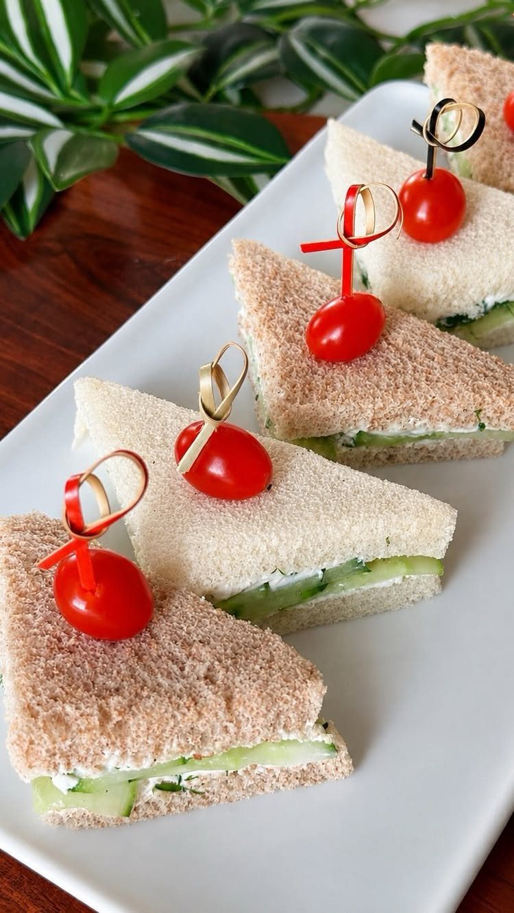 13 Birthday Party Treat Ideas, From Popcorn to Tea Sandwiches 14 Triangular cucumber tea sandwiches with cherry tomatoes on a white platter.