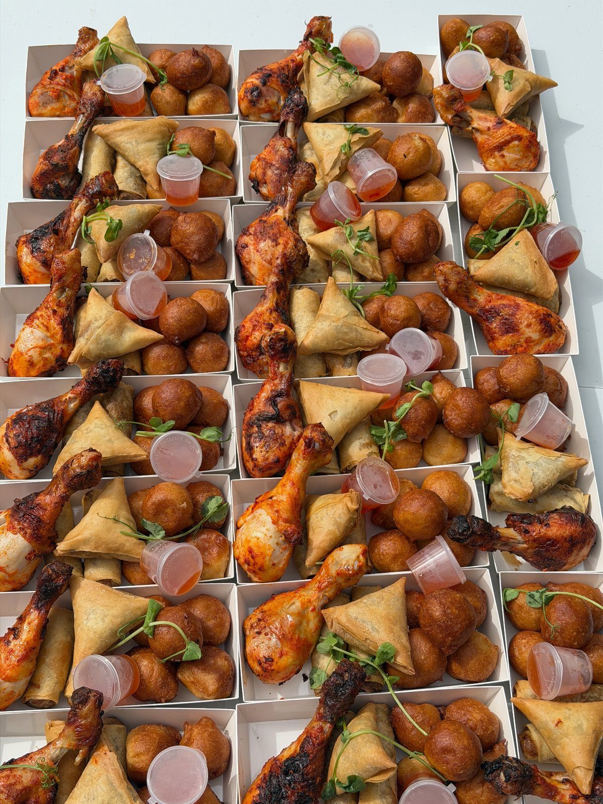 25 Black People Finger Foods 24 Assorted finger foods including chicken drumsticks, samosas, and fried balls in white trays.