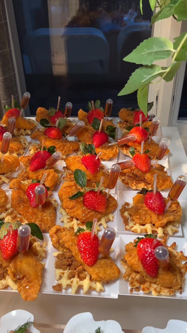 25 Black People Finger Foods 16 Fried chicken and waffle bites topped with strawberries and syrup pipettes on plates.