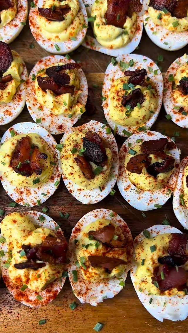 25 Black People Finger Foods 2 Deviled eggs topped with bacon, paprika, and green onions on a wooden board.
