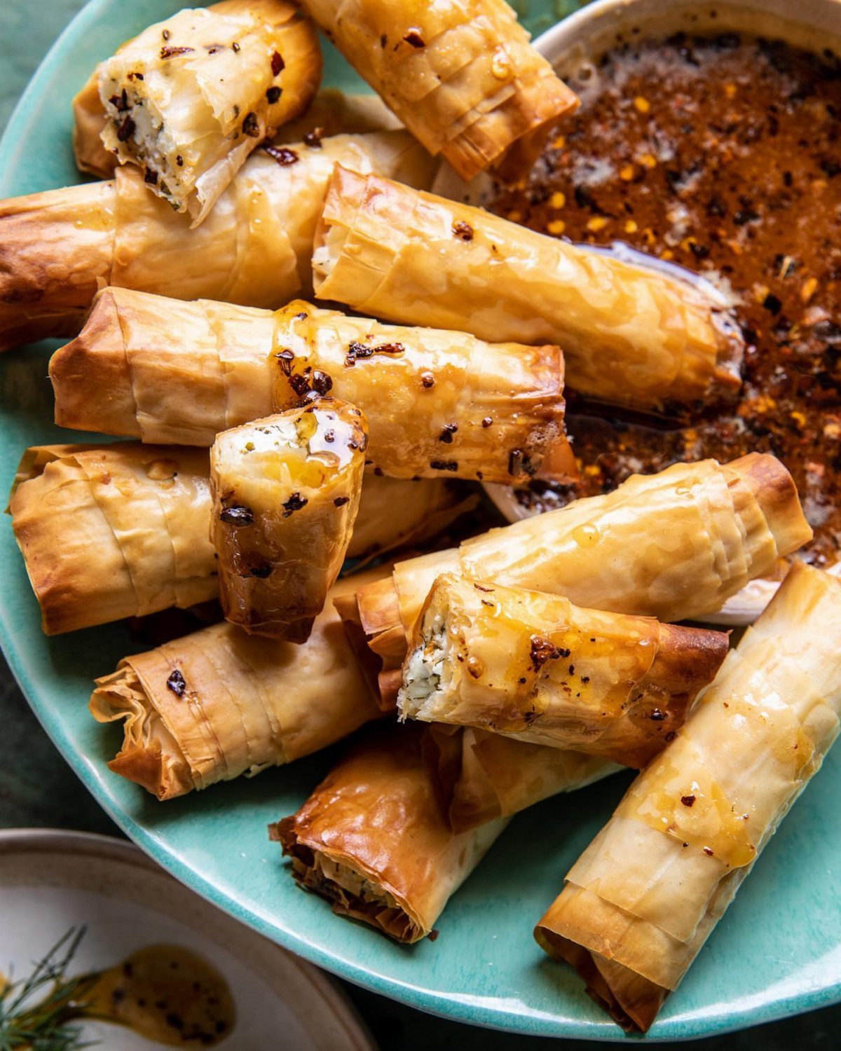 25 Black People Finger Foods 7 Golden brown phyllo feta rolls on a blue plate with hot honey dip.