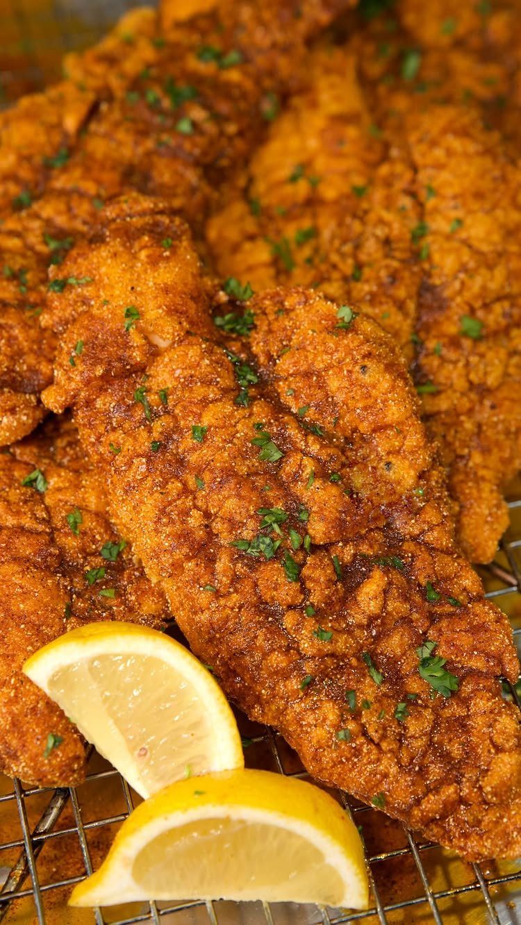 25 Black People Finger Foods 23 Fried chicken strips with parsley and lemon wedges on a metal wire rack