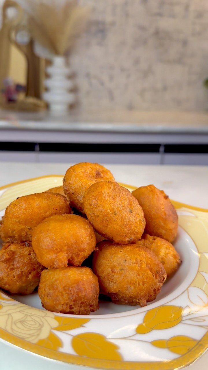25 Black People Finger Foods 10 Golden-brown fried potato balls piled on a white and yellow floral plate.
