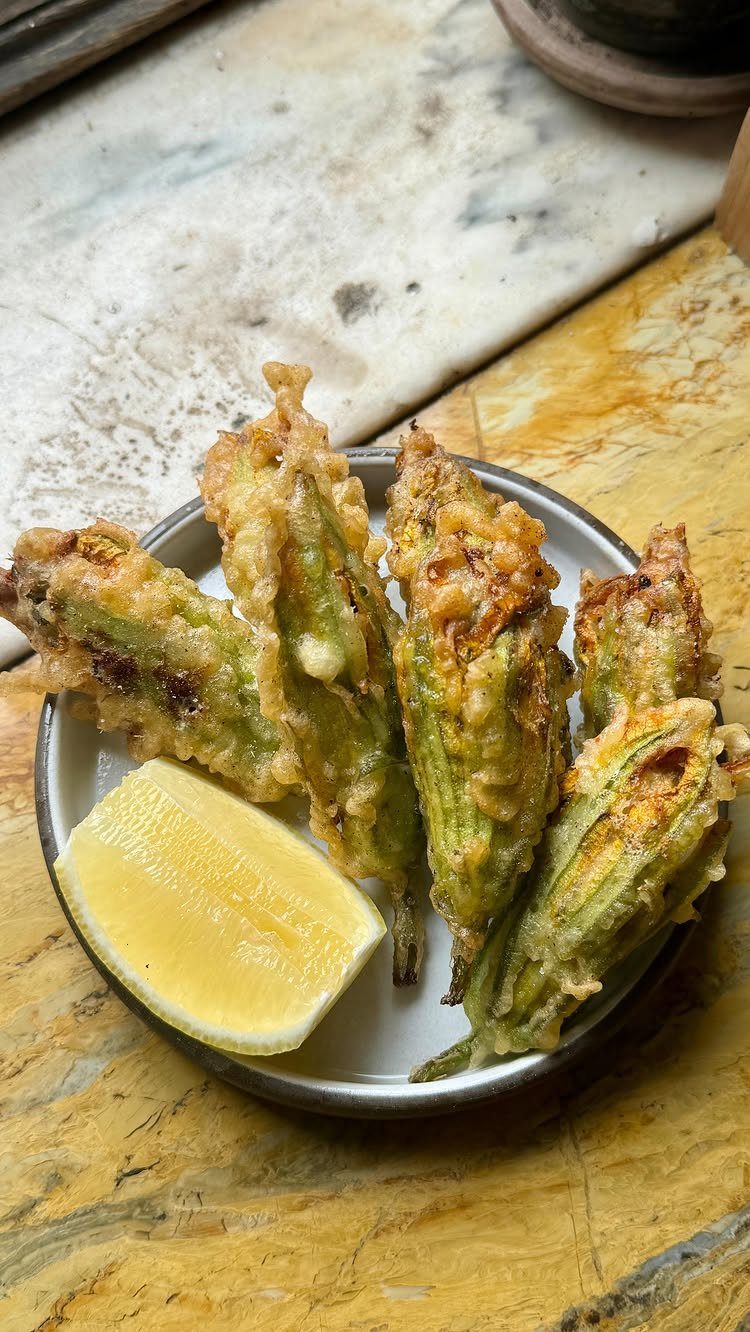 25 Black People Finger Foods 17 Fried battered okra pods on a white plate with a lemon wedge.
