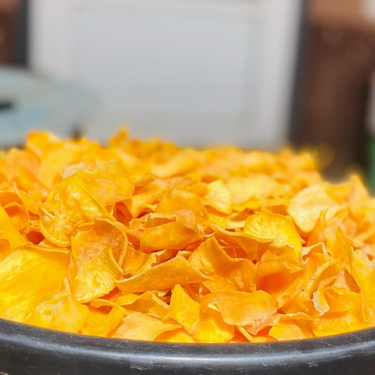 25 Black People Finger Foods 22 Orange plantain chips piled high in a black bowl.
