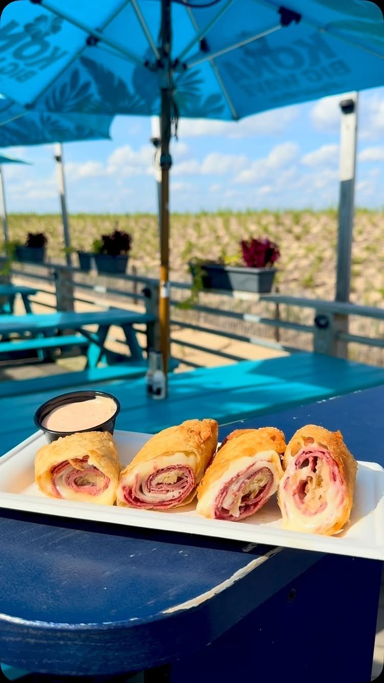 25 Black People Finger Foods 26 Savory ham and cheese pastry rolls on a white plate at an outdoor table.