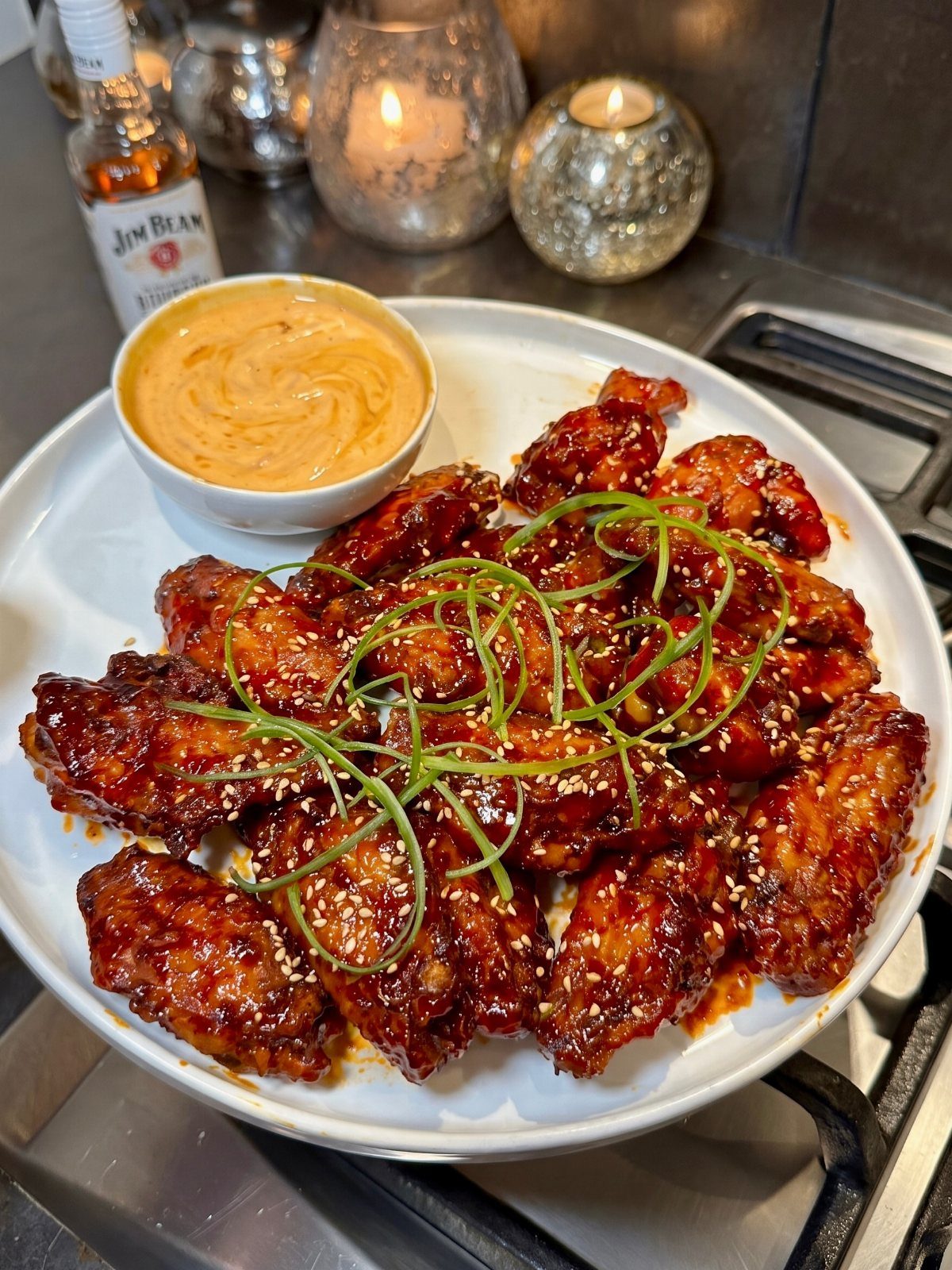25 Black People Finger Foods 6 Glazed chicken wings with sesame seeds and green onions on a white plate.
