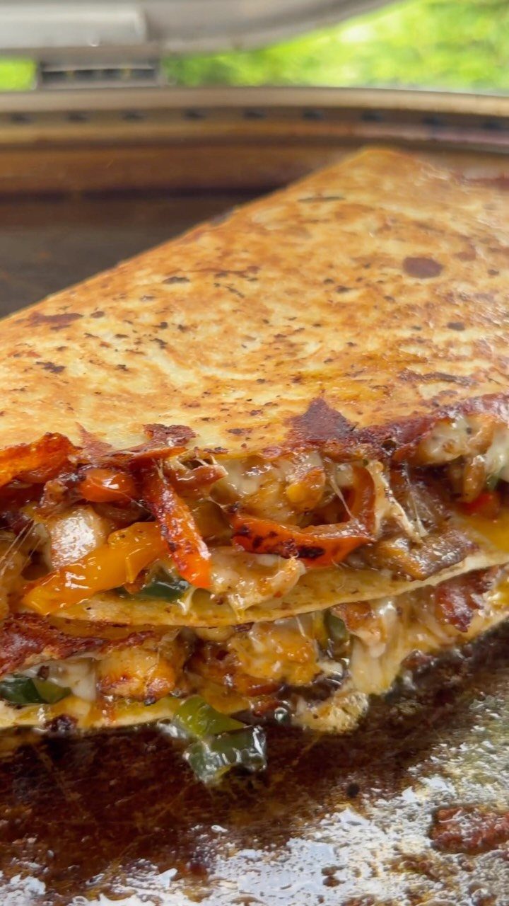 Stacked chicken quesadillas with melted cheese and peppers on a hot grill.