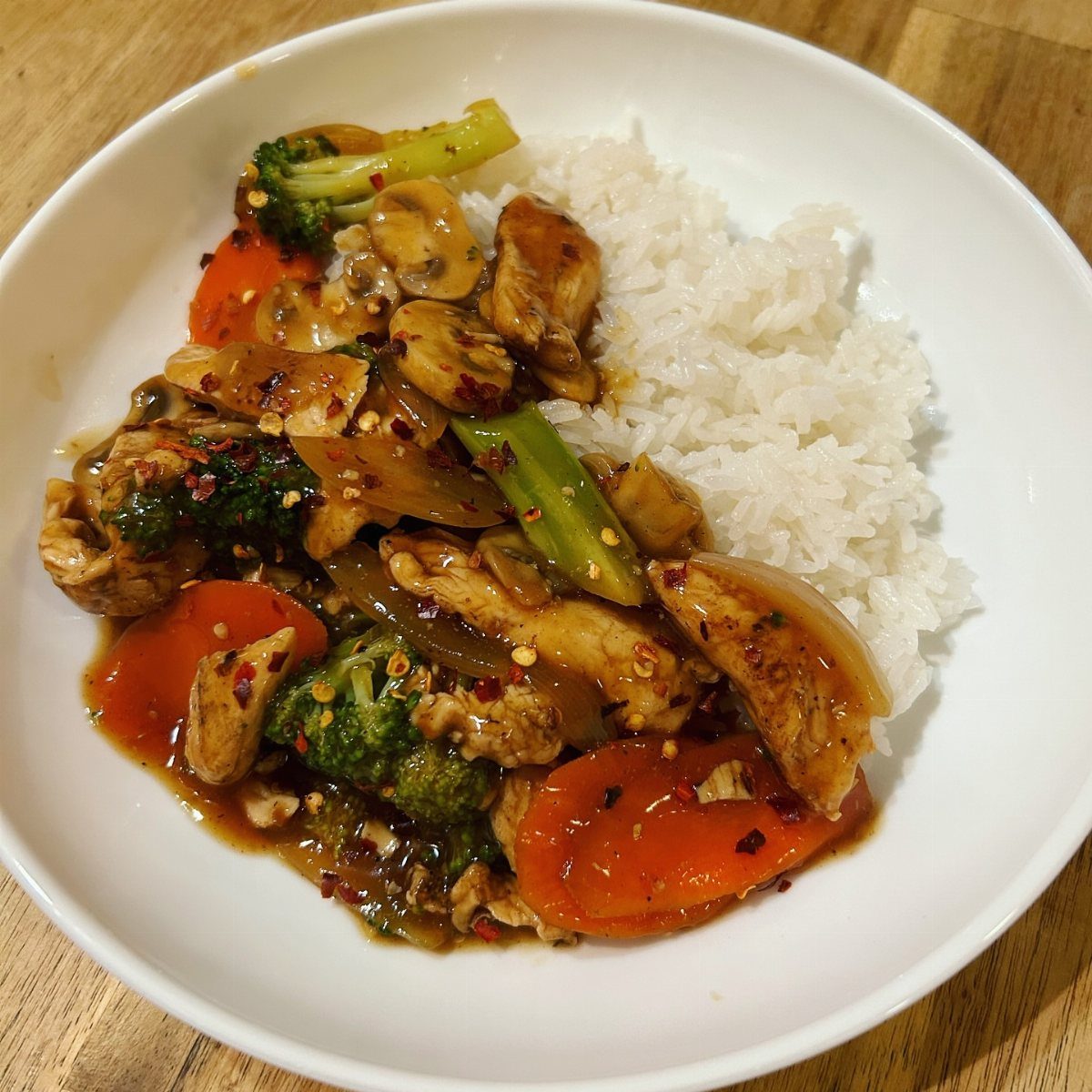 Chicken and vegetable stir-fry with white rice in a white bowl