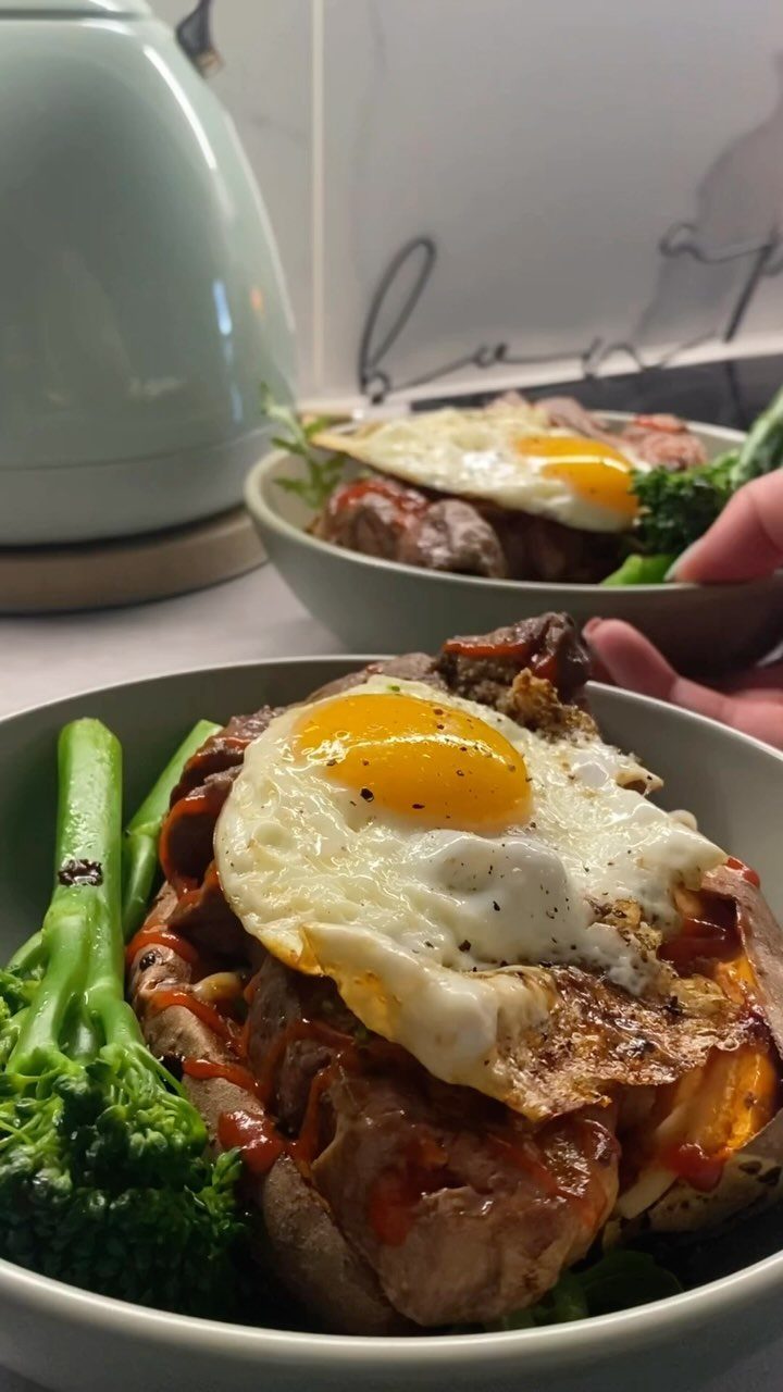 Seared steak topped with a fried egg and served with steamed broccoli.