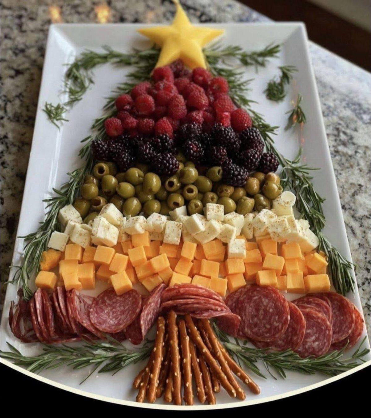 Antipasto platter arranged as a Christmas tree with berries, olives, cheese, and salami.