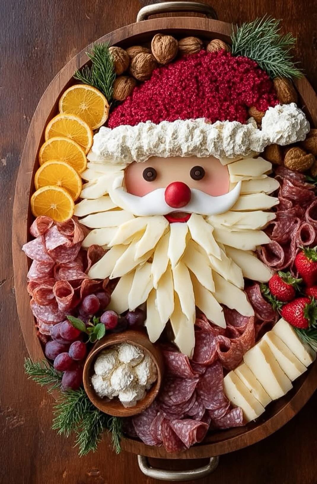Santa Claus face made from cheese, salami, and fruit on a wooden platter.