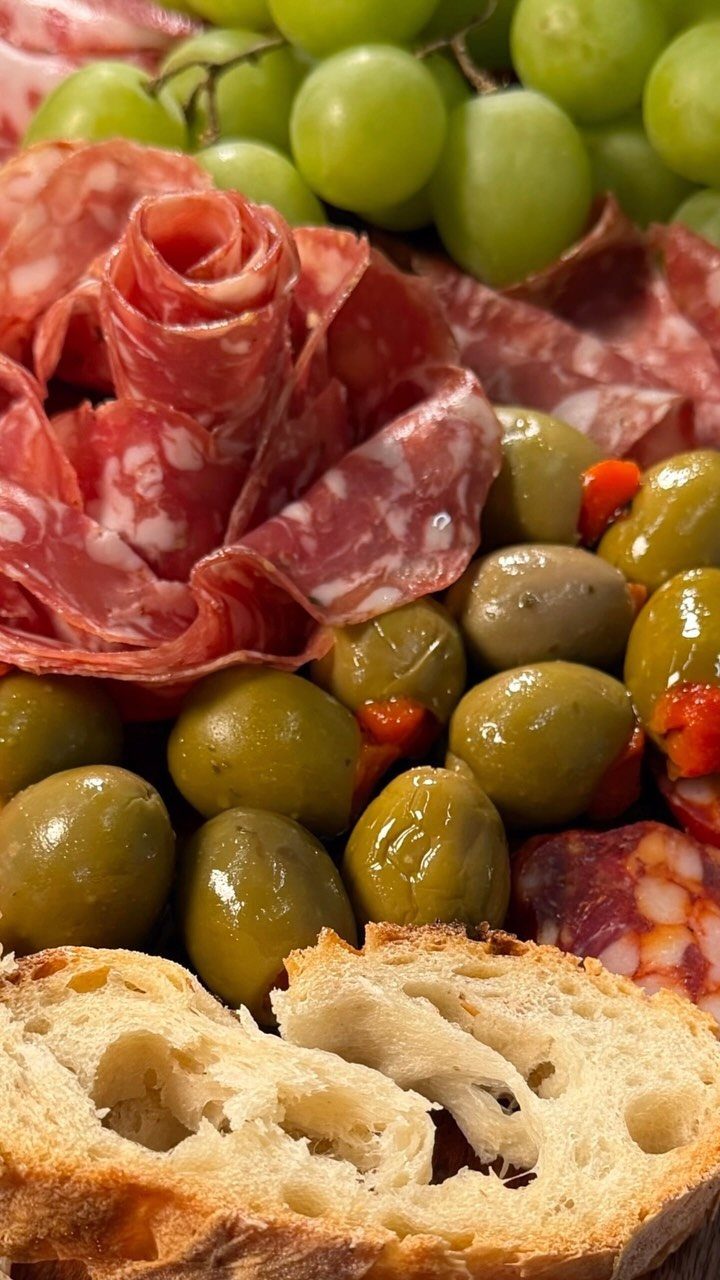 Salami sliced and rolled into a rose with green olives, grapes, and bread.