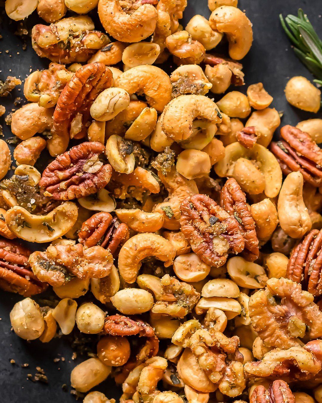 Roasted spiced nuts including cashews and pecans on a dark textured background.