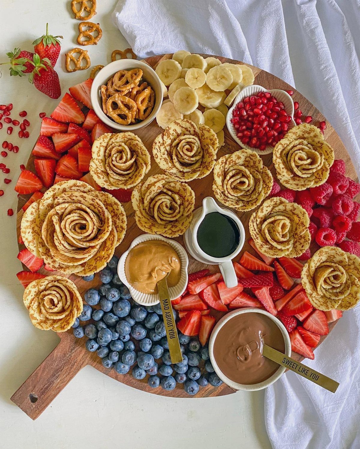 Charcuterie Board Table Ideas: 38 Grazing Tables and Platters 25 Crepe roses on a wooden platter with fresh berries, bananas, and chocolate dip.