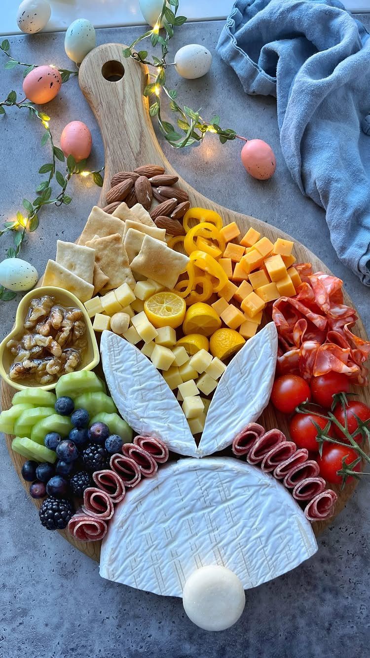Charcuterie Board Table Ideas: 38 Grazing Tables and Platters 20 Bunny-shaped cheese and meat board with pastel eggs and fairy lights on grey surface