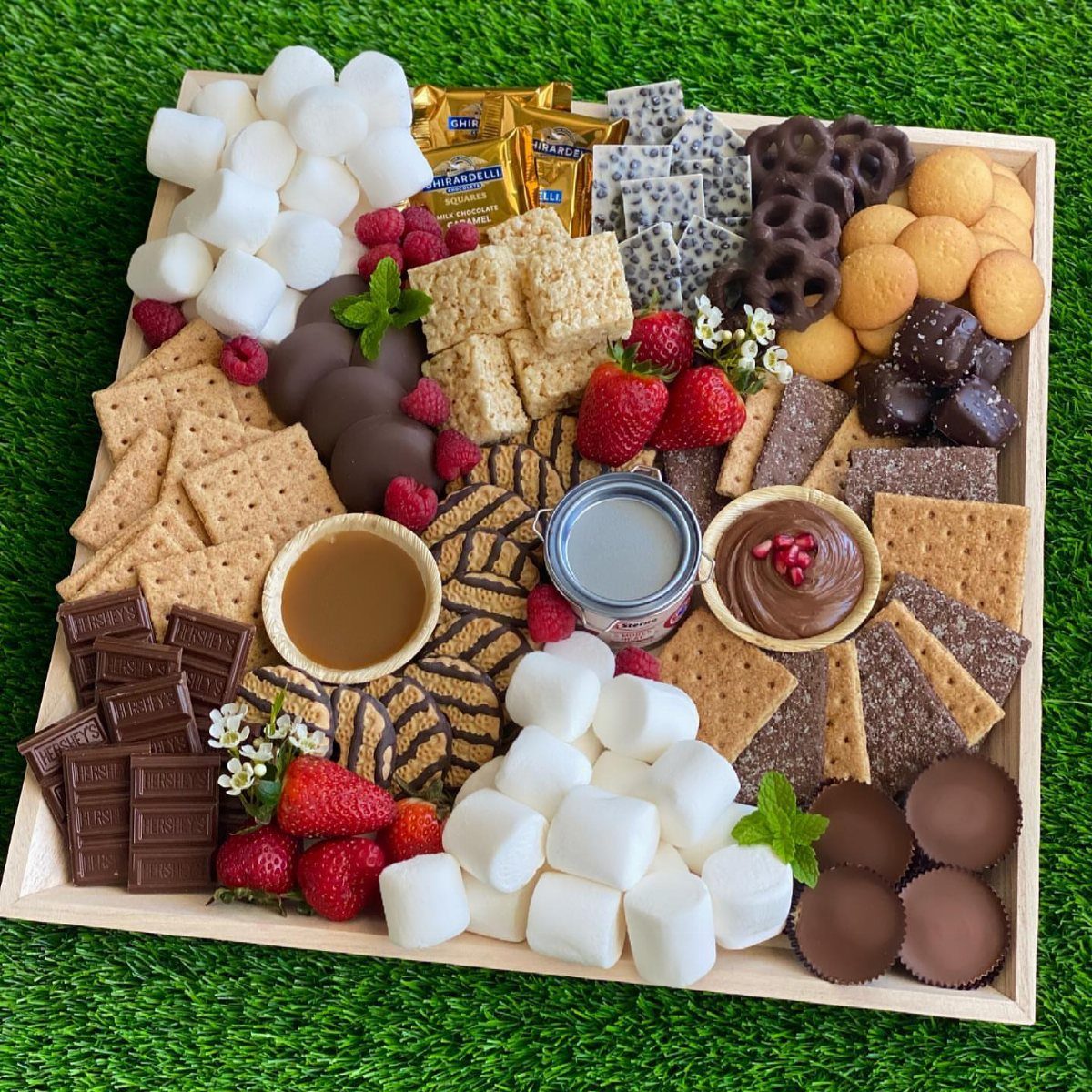 Charcuterie Board Table Ideas: 38 Grazing Tables and Platters 36 S'mores grazing board with marshmallows, graham crackers, chocolate, and fresh berries on grass.