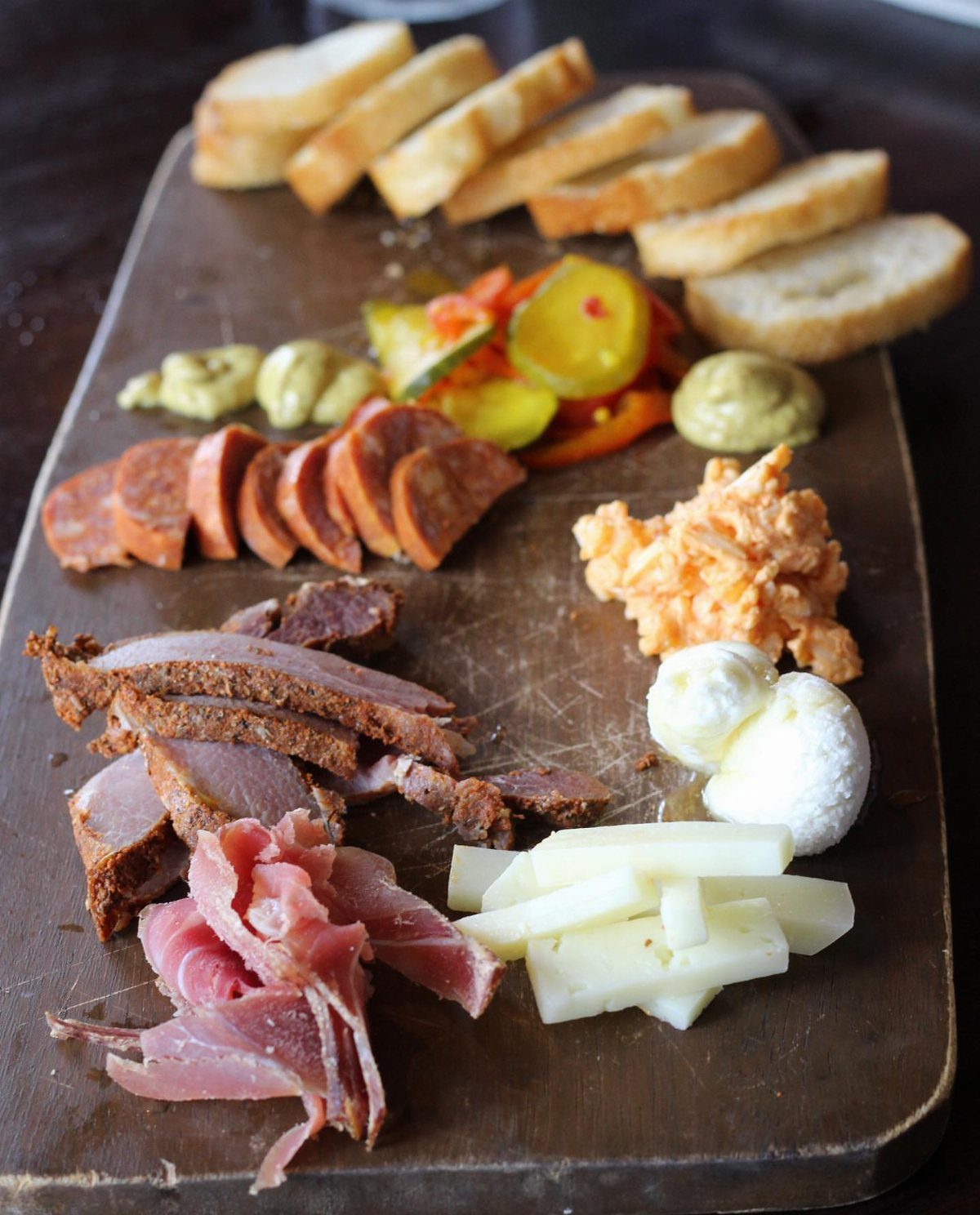 Charcuterie Board Table Ideas: 38 Grazing Tables and Platters 8 Wooden charcuterie board with sliced sausage, pimento cheese, mozzarella, and toasted baguette slices.