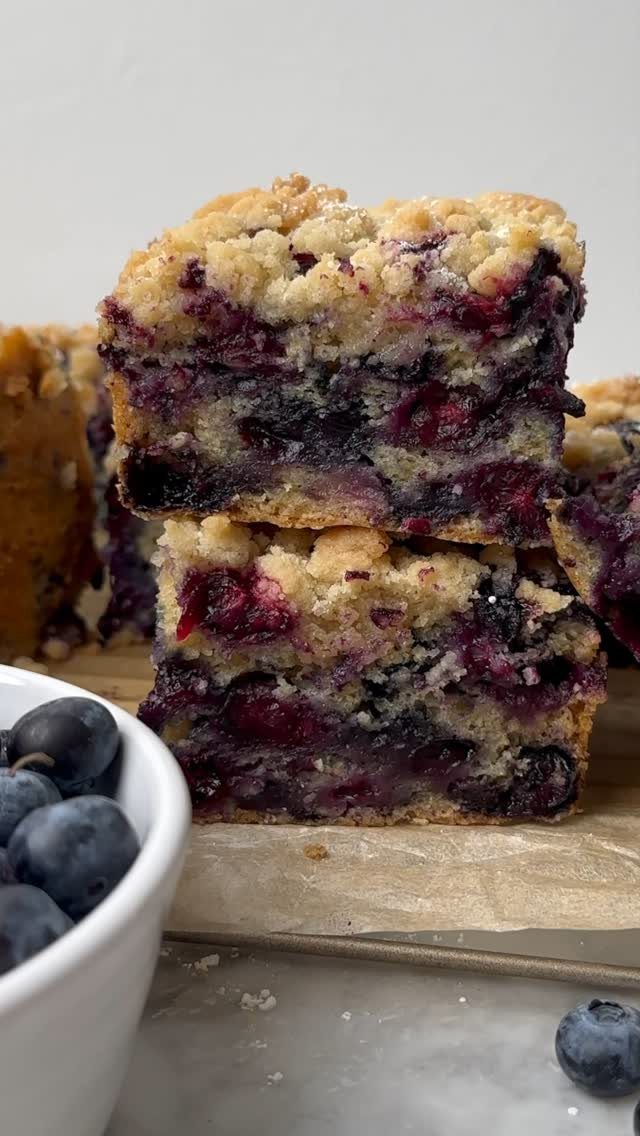 24 Desserts to Make with Blueberries, Cobbler to Cheesecake 25 Stacked blueberry buckle cake squares with crumbly topping and fresh blueberries nearby.