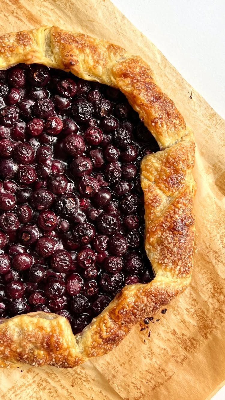 24 Desserts to Make with Blueberries, Cobbler to Cheesecake 19 Blueberry galette with a golden sugared crust on brown parchment paper.