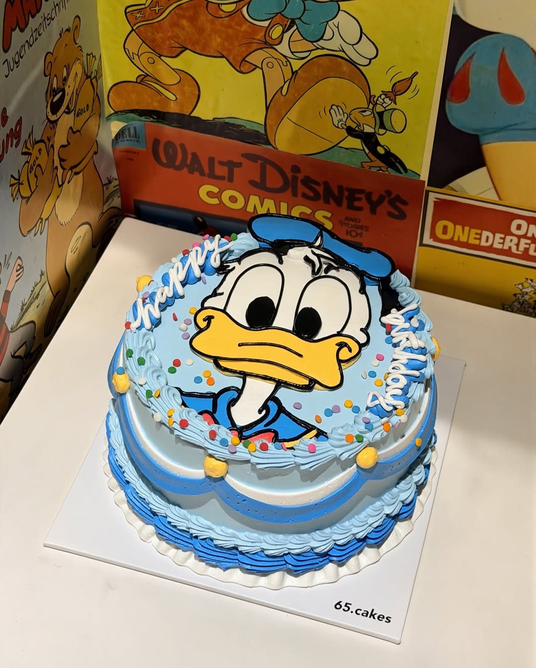 12 Duck Cakes Ideas for Birthdays, From Buttercream to Giant 11 Donald Duck birthday cake with blue frosting and a large character image on top.