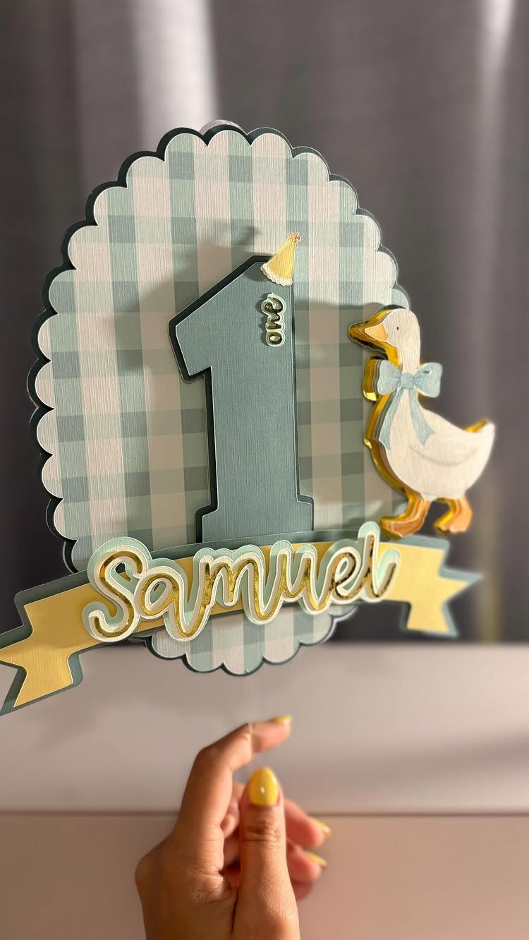 12 Duck Cakes Ideas for Birthdays, From Buttercream to Giant 13 Personalized duck cake topper with number one and name Samuel on yellow banner.