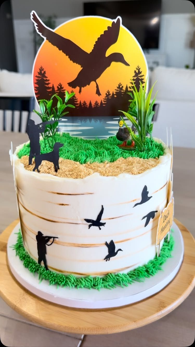 12 Duck Cakes Ideas for Birthdays, From Buttercream to Giant 8 Duck hunting themed cake with hunter silhouettes and a sunset duck topper.