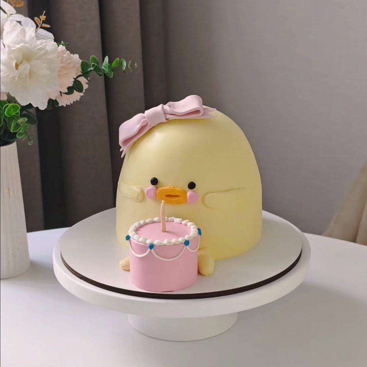 12 Duck Cakes Ideas for Birthdays, From Buttercream to Giant 7 Yellow duck shaped cake with a pink bow and a tiny pink cake.