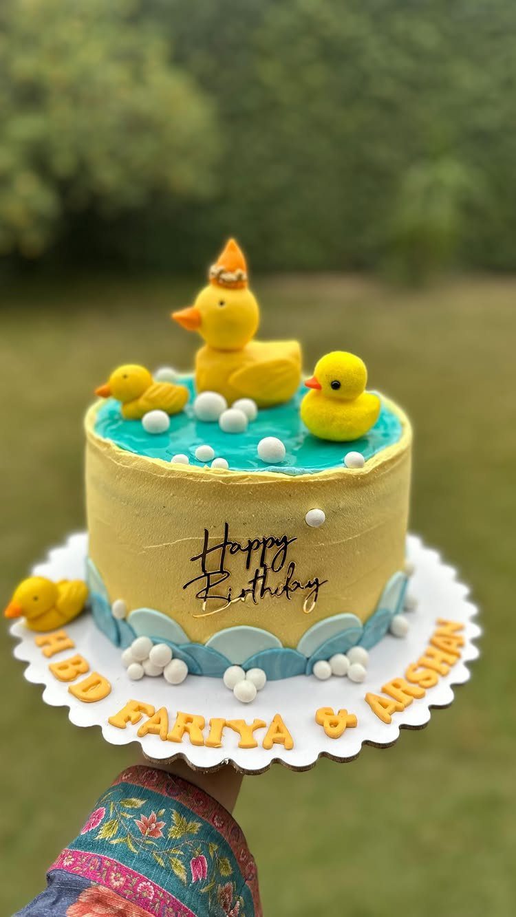 12 Duck Cakes Ideas for Birthdays, From Buttercream to Giant 3 Yellow birthday cake with rubber duck toppers and blue frosting bubbles on a board.