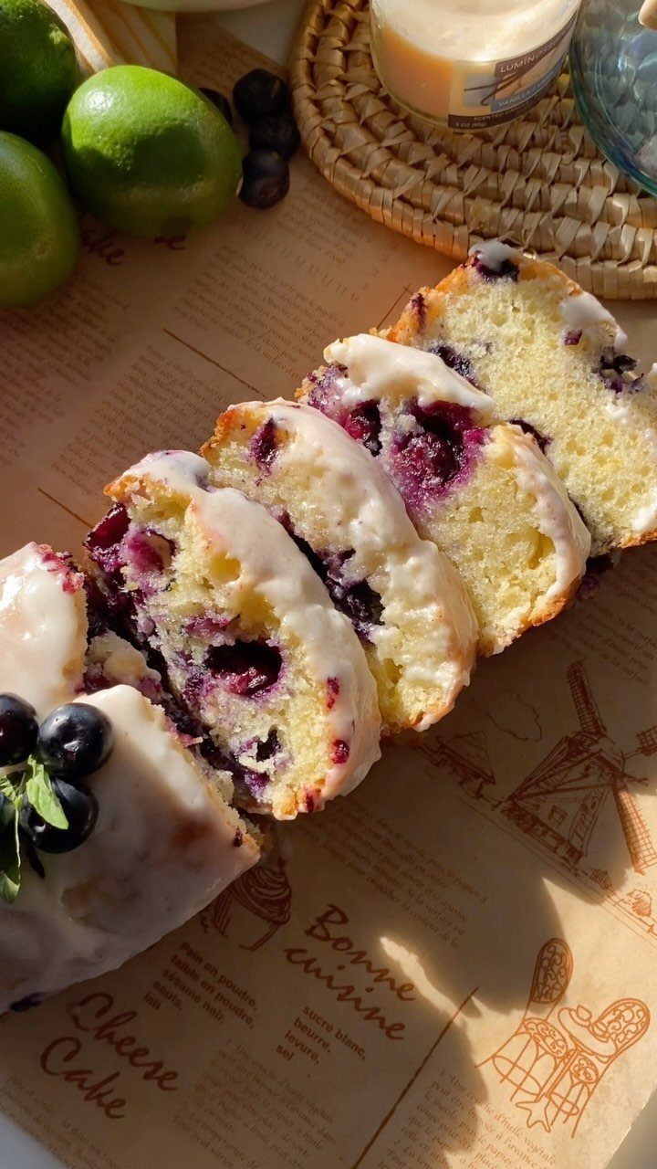 Slices of lemon blueberry bread with white icing on brown parchment paper.