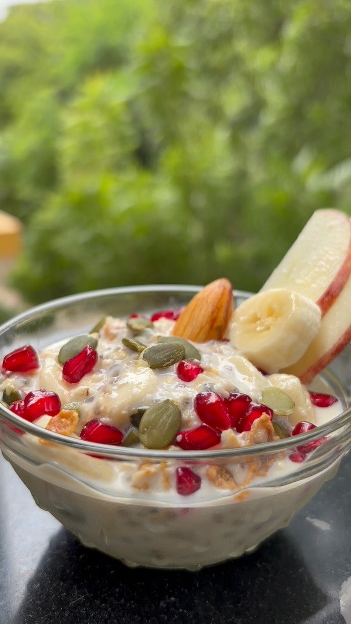 Creamy overnight oats topped with pomegranate, pumpkin seeds, banana, and apple slices.